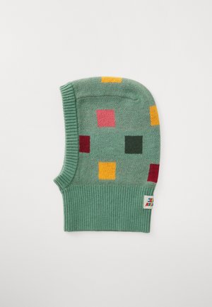 Grønn strikket lue med ribbet bunn, som har fargerike geometriske former i rosa, rød, gul og grønn. Merket er synlig på siden.
