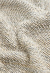 Tessuto intrecciato in beige con toni terrosi, caratterizzato da un motivo a maglia larga e strutturata che mostra sottili variazioni di colore in tutto il tessuto.