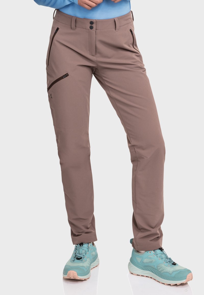 Braune Outdoor-Hosen im Slim Fit mit Reißverschlusstaschen und einem glatten, leichten Stoff. Kombiniert mit türkisfarbenen Wanderschuhen.