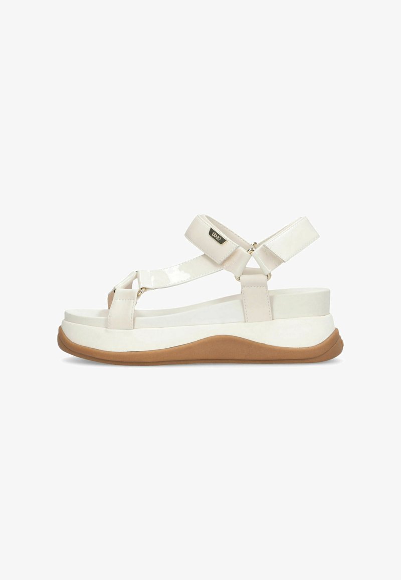 Sandales en cuir verni blanc avec des sangles réglables, une épaisse plateforme blanche et une semelle en caoutchouc brun. Design moderne avec des lignes épurées.