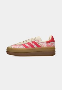 Pink floral-patterned sneaker with beige accents, three red stripes, and a chunky brown sole. Features textured material and padded collar.