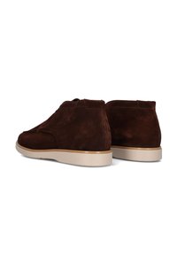 Chaussures de cheville en suede brun avec une finition lisse, présentant une semelle en caoutchouc beige et un design minimaliste. L'arrière montre des détails de couture.