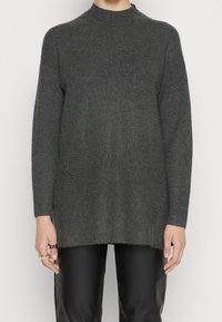 Donkergrijze ribgebreide trui met een hoge halslijn en lange mouwen, heeft een relaxed fit en lichte zijsplitten aan de onderkant.