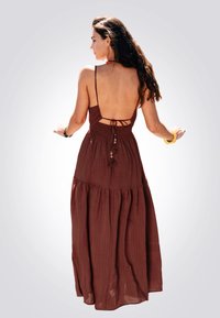 Dieprode maxi-jurk met dunne banden, open rugontwerp, gerimpelde taille, gelaagde rok en gestructureerde stof. Bevat een kwastdetail aan de achterkant.