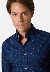 Granatowa koszula z bawełnianej mieszanki, z subtelnym kwiatowym wzorem i czerwonymi akcentami, z kołnierzykiem zapinanym na guziki i białymi guzikami.