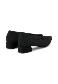 Zapatos negros de punto con parte superior texturizada y un bajo tacón cuadrado de ante negro. Acabado suave y diseño transpirable, adecuados para uso casual.