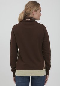 Pullover in cotone marrone con collo alto, orlo inferiore a contrasto crema, polsini a coste e etichetta con marchio sul collo posteriore.