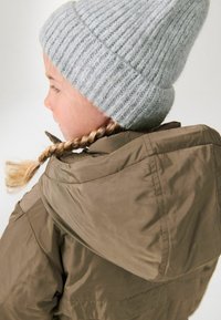 Veste marron avec un col haut et un bonnet en tricot gris. Le bonnet présente une texture côtelée, tandis que la veste a une finition lisse et brillante.