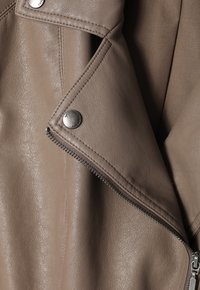 Light taupe faux leather jacket with zip closure, snap buttons, and a diagonal collar design. Features textured fabric and contrasting stitching.
