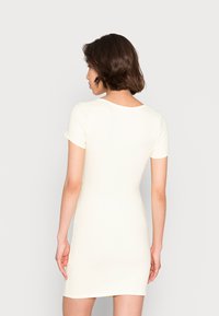 Vestido mini justo e canelado em tecido leve e macio de amarelo claro, com mangas curtas e decote arredondado, apresentando uma textura suave.