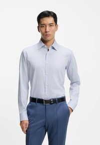 Camicia a righe azzurro chiaro e bianco con colletto button-down, maniche lunghe e vestibilità elegante, abbinata a pantaloni blu scuro a righe sottili e cintura nera.