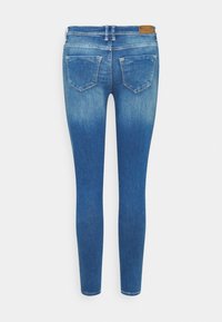 Úzké džíny v tmavě modrém denimu s přechodem barev. Mají dvě zadní kapsy a koženou značku na pásku. Hladká struktura po celém povrchu.