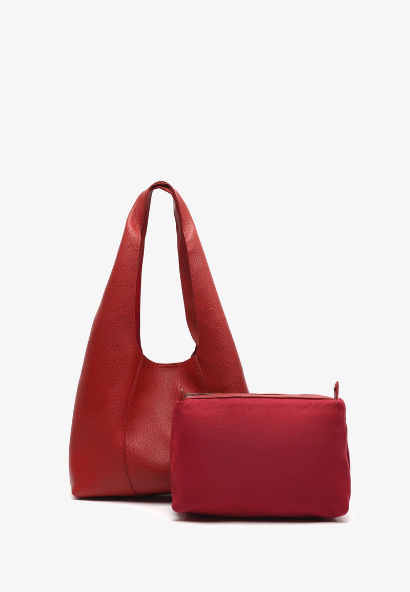 Borsa a spalla morbida in pelle rossa con tracolla larga accanto a una piccola pochette rettangolare rossa con cerniera su sfondo bianco.