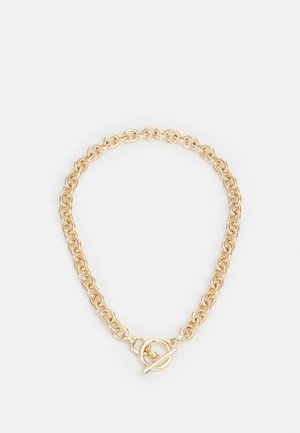 Collier chaîne doré à maillons larges entrelacés avec un fermoir à bascule rond sur un fond clair.