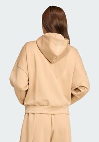 Beige hoodie met een relaxte pasvorm, textuurstof, geribbelde manchetten en zoom, met een klein merketiketje op de achterkant van de capuchon.