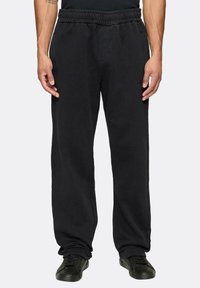 Juodi sportiniai kelnes, pagamintos iš minkštos medžiagos, su elastinga juosmens juosta, šoninėmis kišenėmis ir laisvu, tiesiu kirpimu.