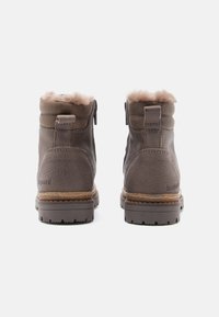 Bottes d'hiver en cuir marron avec doublure en fourrure, semelles robustes, languettes arrière et fermetures éclair sur les côtés, vue de l'arrière sur un fond blanc.