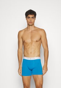 Modri bombažni bokserice z belim elastičnim pasom, na katerem je logo "TOMMY HILFIGER". Gladka tekstura in prilegajoča se zasnova.