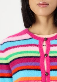 Multikleurige cardigan met gedurfde strepen in roze, blauw, groen en oranje. Heeft een donzige textuur en twee decoratieve knopen aan de voorkant.