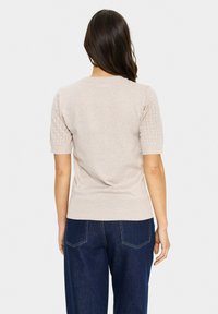 Hellbeige kurzärmliger Pullover mit Rundhalsausschnitt; strukturierte, gestrickte Ärmel mit einem Rautenmuster; weicher, glatter Stoff.