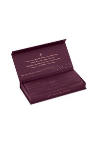 Scatola viola scuro aperta con testo dorato che descrive una maschera per gli occhi in seta per il relax e le routine di bellezza all'interno.