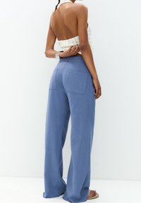 Spodnie o szerokich nogawkach w jasnoniebieskim kolorze, z dwiema tylnymi kieszeniami i luźnym krojem. Szwany dół jest lekko postrzępiony, co nadaje im swobodny wygląd.