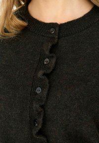 Cardigan en laine sombre avec un col côtelé, une patte de boutonnage ondulée avec des boutons noirs, et une finition douce et texturée.
