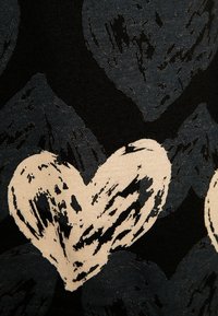 Abstrakcyjne kształty serc w odcieniach beżu i ciemnoszarości z chropowatą, przypominającą pociągnięcia pędzla teksturą na czarnym tle tkaniny.