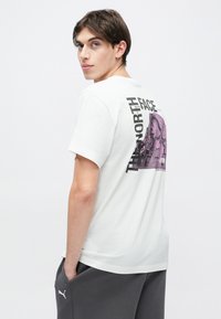 Λευκό βαμβακερό t-shirt με μεγάλο μοβ γραφικό βουνού και μαύρο κείμενο που γράφει "THE NORTH FACE" στην πλάτη. Χαλαρή εφαρμογή.