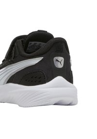 Scarpa sportiva nera con tomaia sintetica liscia, accenti argento e suola in gomma bianca. Presenta una linguetta sul tallone per indossarla facilmente.