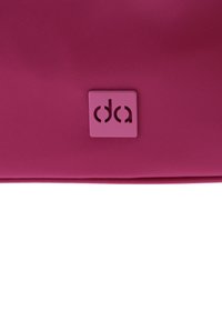 Bolso de mano de nylon rosa con una superficie texturizada y un logo cuadrado en la esquina inferior. Cierre de cremallera y diseño elegante y minimalista.