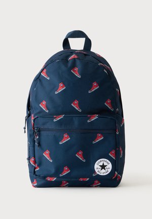 Granatowy plecak z czerwonymi wzorami trampków oraz przednią kieszenią na zamek z okrągłym białym logo Converse All Star.