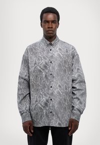 Shirt featuring a grey and black snake-skin print design, button-up front, long sleeves, and a relaxed fit made from lightweight fabric.