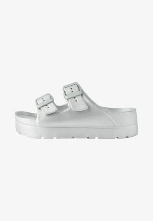 Biele, textúrované šľapky so župankami a dvomi nastaviteľnými prackami, hrubou platformovou podrážkou a zaoblenou špičkou. Vyznačujú sa lesklým kovovým povrchom.