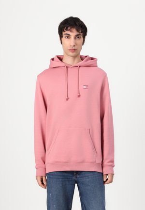 Roze hoodie met trekkoorden, kangoeroe zak, ribgebreide manchetten en zoom. Zachte textuur en minimalistisch logo op de borst.