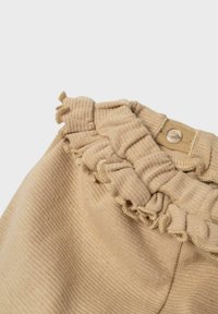 Shorts in tessuto beige con vita arricciata e chiusura a bottone. La texture è liscia con dettagli a costine verticali.