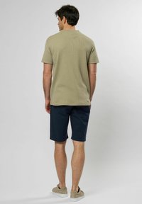 Lyhythihainen oliivinvihreä teksturoitu polo, yhdistetty tummaankansiin. Beige tennarit viimeistelevät kokonaisuuden. Yksinkertainen ja rento muotoilu.
