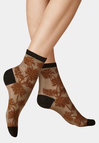 Durchsichtige braune Socken mit einem Palmenblattmuster, featuring eine einfarbige schwarze Ferse und Spitze sowie ein schwarzes geripptes Bündchen.