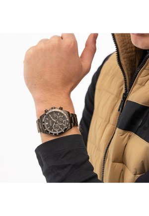 Schwarze Edelstahl-Chronographenuhr mit rundem Zifferblatt, dunklem Ziffernblatt und mehreren Unterziffern, getragen an einem Handgelenk mit einem schwarzen Langarmhemd.