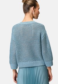Maglione lavorato a maglia blu chiaro con un design morbido e testurizzato, dotato di un orlo a coste e maniche a tre quarti, presentato da dietro.