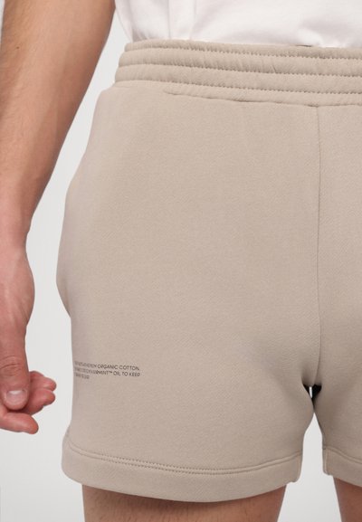 Beige Bio-Baumwollshorts mit elastischem Bund, die am Saum mit einem dezenten Muster und einer weichen, strukturierten Oberfläche ausgestattet sind.
