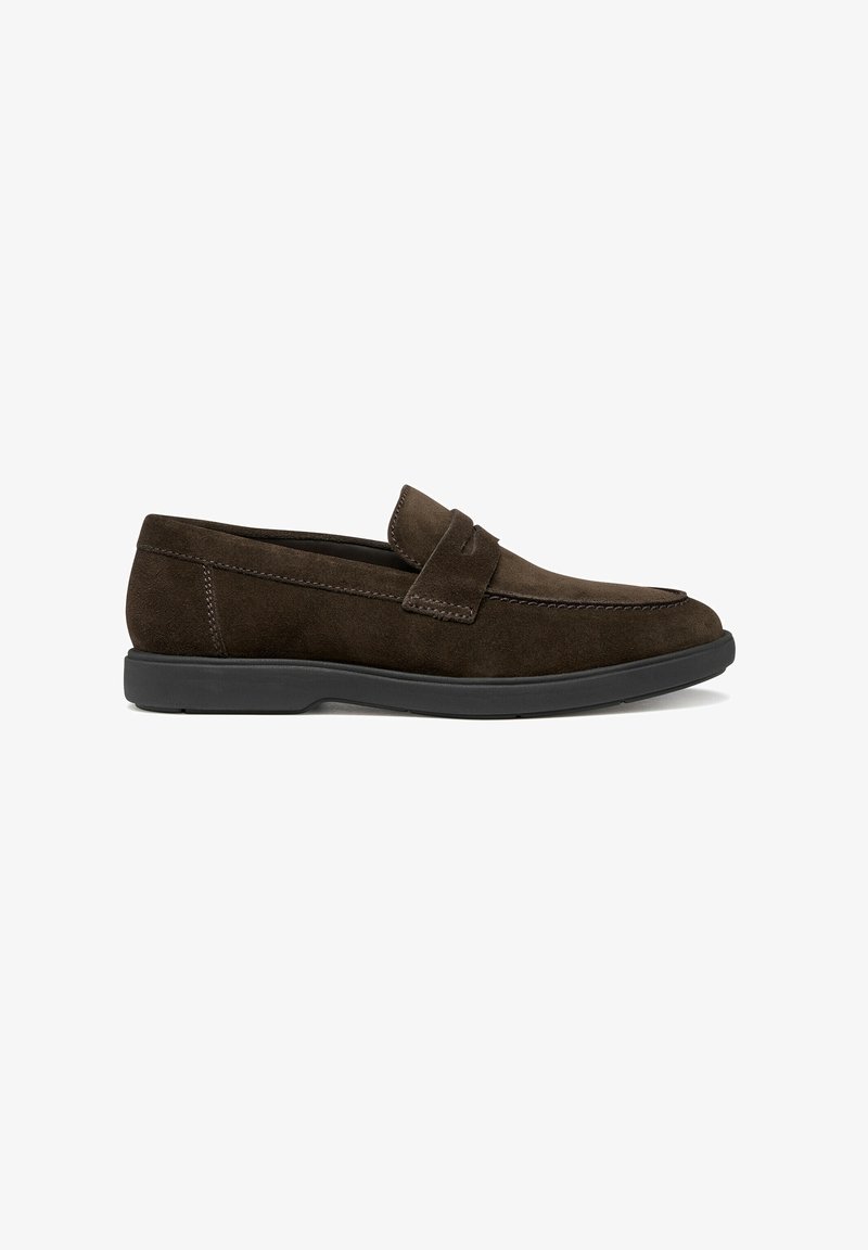 Mocassins en daim marron avec une semelle plate en caoutchouc noir, présentant des détails cousus et un design de bout arrondi lisse.