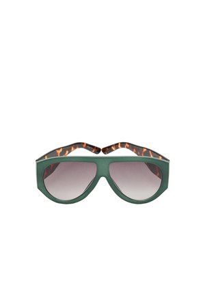 Zielone, oversize'owe okulary przeciwsłoneczne z ciemnymi gradientowymi szkłami i zausznikami w wzór żółwia.