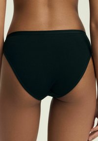 Czarne bawełniane bikini o wysokim kroju nogawki i elastycznym pasku w talii, charakteryzujące się gładką fakturą i brakiem widocznych wzorów.