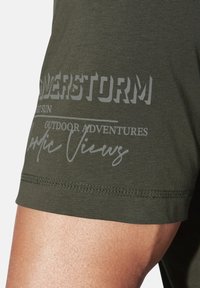 Olive green short-sleeve t-shirt made of cotton. Features printed text in light gray, including "POWERSTORM" and "OUTDOOR ADVENTURES."
