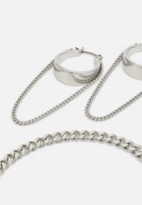 Silberfarbener Schmuckset mit klobigen Creolen und einer dicken Kettenhalskette, alle mit polierter Metalloberfläche und verbundenen Designs.