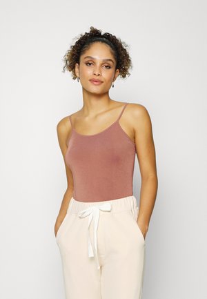 Body na cor rosa envelhecido com alças finas tipo espaguete, combinado com calças creme de cintura elástica com um accentuador de laço branco.