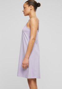Robe sans manches lilas en tissu doux, avec un design simple, des bretelles ajustables et une coupe au genou. Aucune motif ni accent visible.
