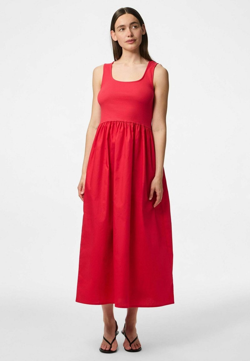 Sarkans bez piedurknēm maksi kleita ar kvadrātveida dekoltē un savilktu jostu. Izgatavota no gludas auduma, tai ir plūstoša svārku daļa un vienkāršs dizains.