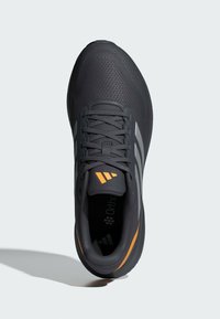 Schwarzer Sportschuh aus Mesh-Material, mit orangen Akzenten und drei weißen Streifen an der Seite. Schnürdesign und gepolsterte Sohle.